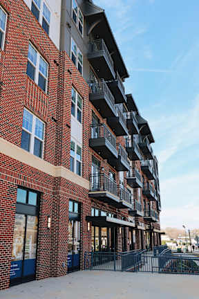 A red brick building with balconies and a black gate in front.