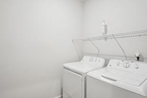 Two white washing machines in a laundry room.