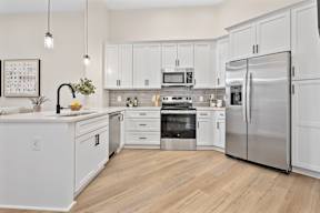 A modern kitchen with white cabinets and stainless steel appliances.