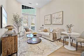 A living room with a white couch, a coffee table, and a TV on the wall.