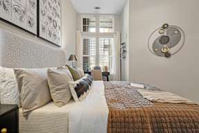 A bedroom with a bed, pillows, and a wall art.