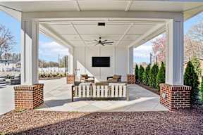 A covered patio with a ceiling fan and a flat screen TV.