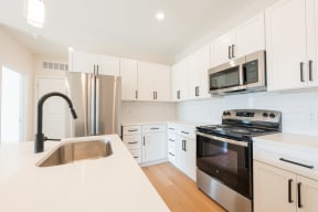 a kitchen with white cabinets and stainless steel appliances_North End Apartments