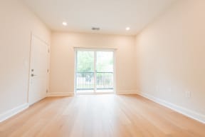 a living room with wood floors and a door to a balcony The North End Apartments