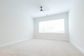 an empty room with white walls and a large window