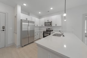 a kitchen with white cabinets and a white counter top at The Fitzgerald, Spartanburg