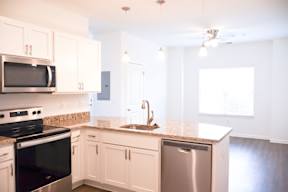 A kitchen with white cabinets and a granite countertop.