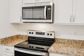 A black microwave oven mounted above a stove in a kitchen.