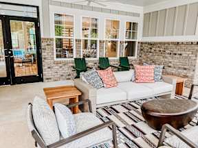 A patio with a white couch and a wooden table.