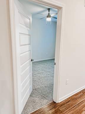 A room with a ceiling fan and a door.