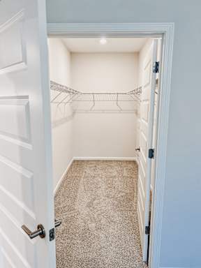 A white door is open to a small, empty room with a carpeted floor.