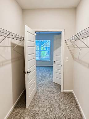 A hallway with a white door leading to a balcony.