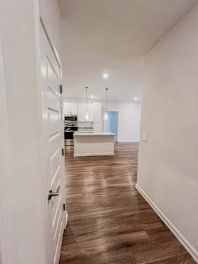 A long hallway with a kitchen area at the end.