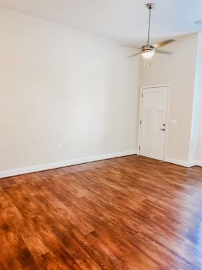 an empty living room with wood floors and a ceiling fan