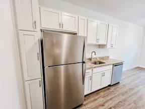 A kitchen with a stainless steel refrigerator and white cabinets.