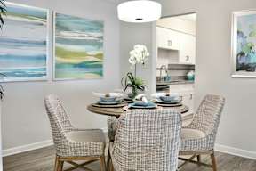 A dining room with a table set for four and two chairs.