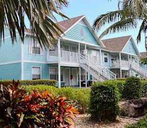 A blue house with a white balcony and stairs leading to the front door.