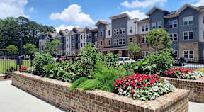 A row of houses with a brick wall and flowers in front.