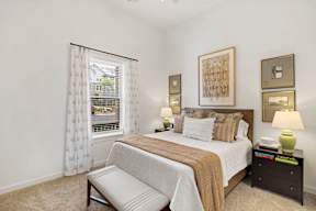 A bedroom with a large bed and a window with curtains.