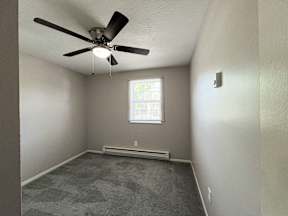 an empty room with a ceiling fan and a window