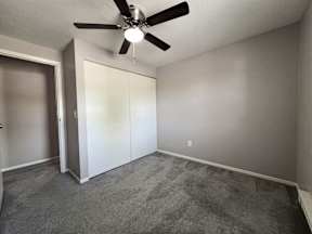 an empty living room with a ceiling fan and a closet