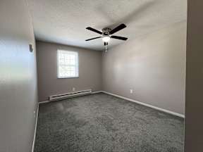 an empty room with a ceiling fan and a window