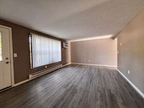 an empty living room with wood floors and a window