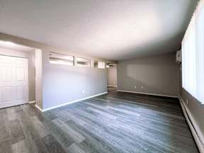 an empty living room with grey and white walls and wood floors