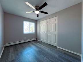 an empty living room with a ceiling fan and a window