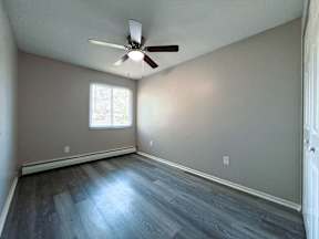 an empty living room with wood floors and a ceiling fan