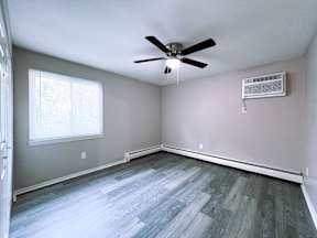 an empty living room with wood floors and a ceiling fan
