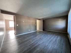 an empty living room with wood flooring and a window