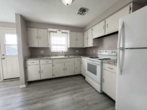 an empty kitchen with white appliances and white cabinets
