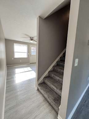 an empty living room with stairs and a ceiling fan