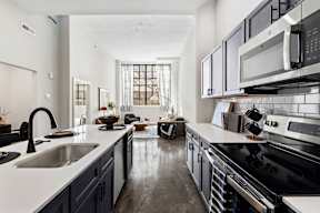 a kitchen with white counters and black appliances and a large window