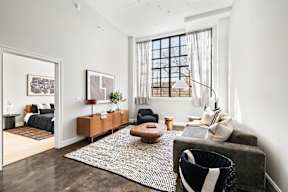 a living room with a gray couch and a rug and a window
