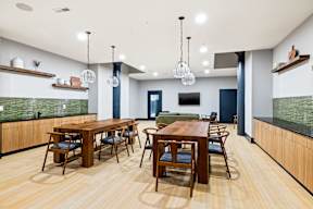 a communal dining room with tables and chairs and a kitchen with a tv
