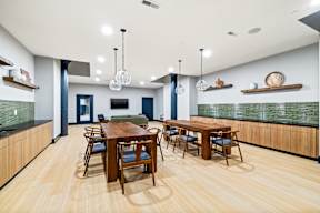 a communal dining room with tables and chairs and a tv