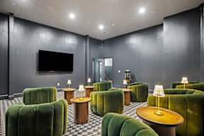 a living room with green chairs and a tv