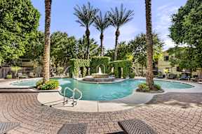 A pool surrounded by palm trees and bushes.