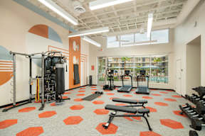 A gym with orange and white walls and a variety of equipment.
