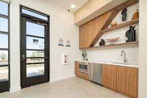 A kitchen with a black door and wooden cabinets.