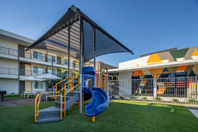 A playground with a blue slide and a black canopy.