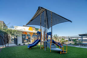 A playground with a blue slide and a canopy.