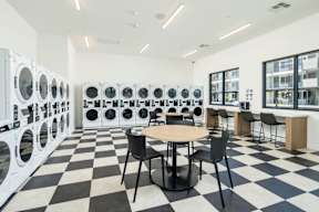 A laundromat with a checkered floor and rows of washing machines.