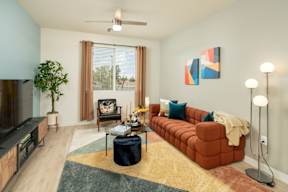 A living room with a red couch, a television, and a potted plant.