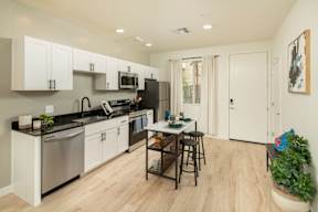 A kitchen with white cabinets and a black refrigerator.