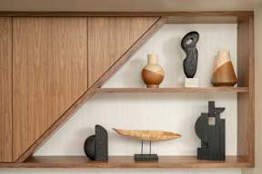 A collection of abstract sculptures are displayed on shelves in a room.