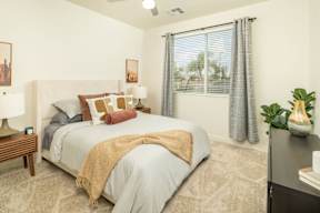 A bedroom with a large bed and a window with curtains.