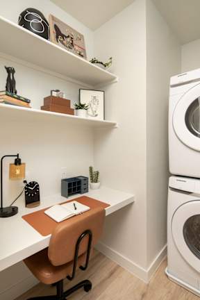 A small room with a desk, chair, and a washing machine.